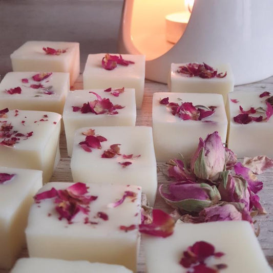 Wax melts with rose petals on top, displayed with a wax melt burner in the background.